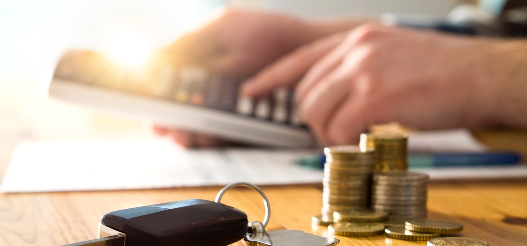 Man calculating costs with money and car keys 